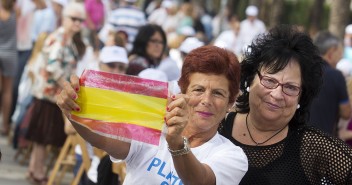 Asistentes al acto muestran orgullosas la bandera de España