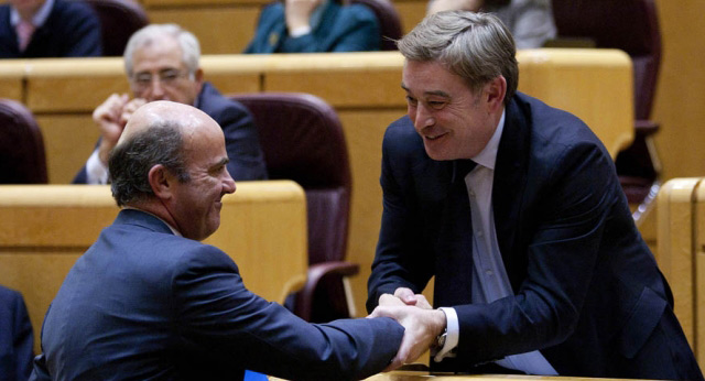 El ministro de Economía, Luis de Guindos, saluda al portavoz del Grupo Popular en el Senado, José Manuel Barreiro