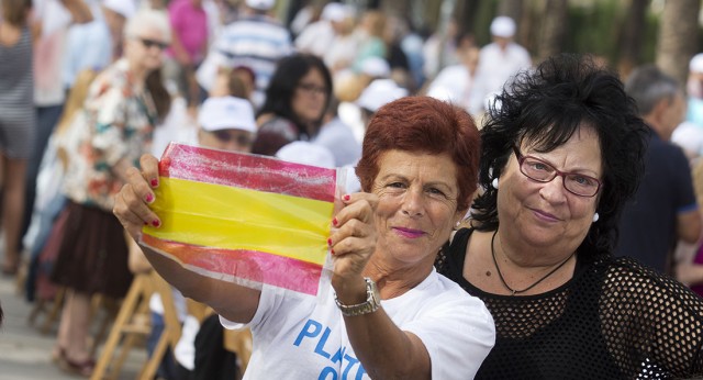 Asistentes al acto muestran orgullosas la bandera de España